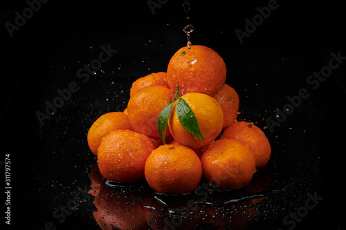 Tangerines mandarines with water drops on black background. New Year 2020