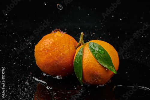 Tangerines mandarines with water drops on black background. New Year 2020