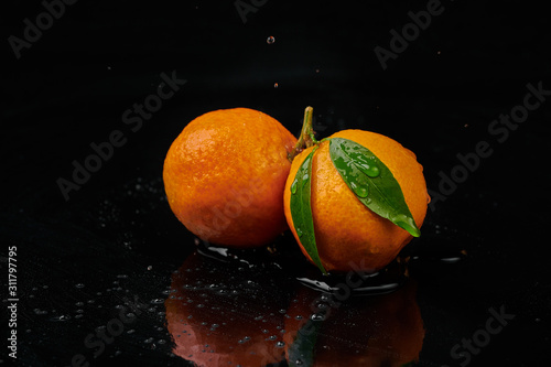 Tangerines mandarines with water drops on black background. New Year 2020