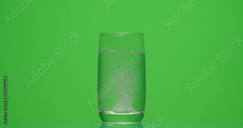 patient throws aspirin into a glass of water on a green background