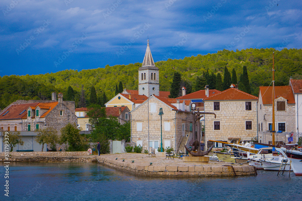 Naklejka premium Zlarin, Croatia / 18th May 2019: Seafront view on Zlarin, boats, harbour, Church of Holy Mary