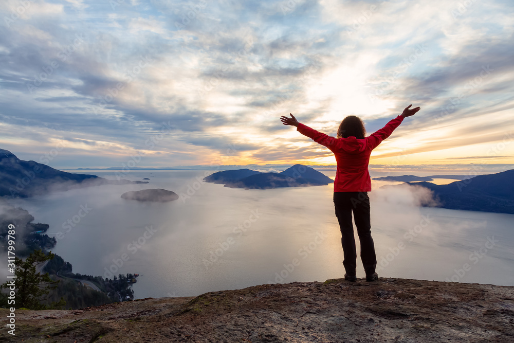 Adventurous Caucasian Girl sitting on top of a mountain during a colorful winter sunset. Taken on Tunnel Bluffs Hike, North of Vancouver, BC, Canada. Adventurous Caucasian Girl sitting on top of a mountain during a colorful winter sunset. Taken on Tunnel Bluffs Hike, North of Vancouver, BC, Canada.