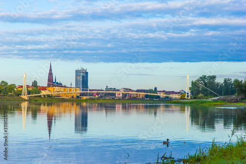 Osijek / Croatia: 10th May 2019: Cityscape of Osijek in sunrise - cathedral, pedestrian bridge and river Drava