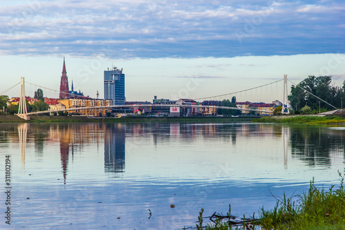 Osijek / Croatia: 10th May 2019: Cityscape of Osijek in sunrise - cathedral, pedestrian bridge and river Drava