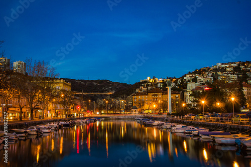 Rijeka, Croatia / December 10th 2018: Boats in river Rjecina and Delta in sunset and blue hour