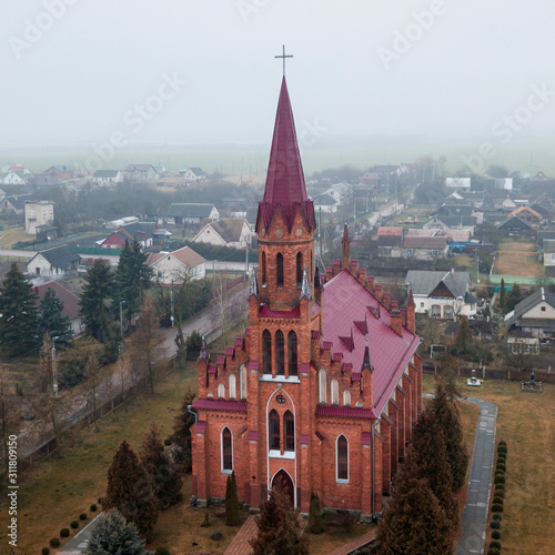 Aerial view neogothic red catholic church of the Heart Jesus in small Belarusian village Stolovichi. photo