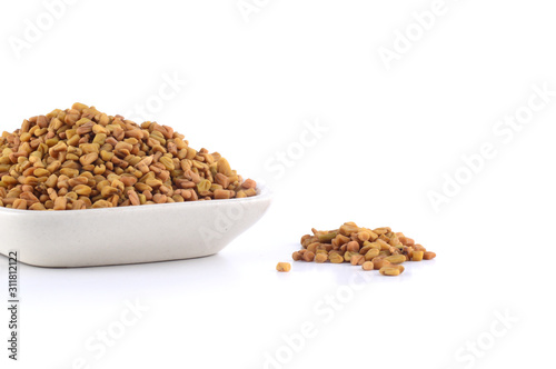 Fenugreek seeds in white plate isolated on white background photo