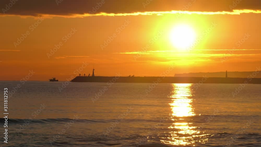 Sun rising over sea with motor boat leaving harbor Sun rising over sea with motor boat leaving harbor