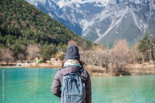 Young woman traveler traveling at Blue Moon Valley, landmark and popular spot inside the Jade Dragon Snow Mountain Scenic Area, near Lijiang Old Town. Lijiang, Yunnan, China. Solo travel concept