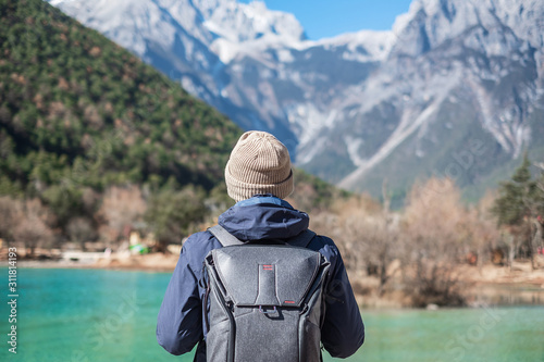 Young man traveler traveling at Blue Moon Valley, landmark and popular spot inside the Jade Dragon Snow Mountain Scenic Area, near Lijiang Old Town. Lijiang, Yunnan, China. Solo travel concept photo