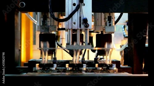 Close-up of industrial machinery to convey raw materials for the production of clear plastic bottles through a heating process, industry 4.0