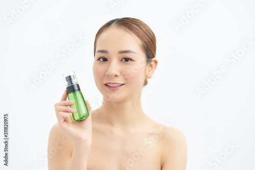 Happy young beautiful woman showing cosmetic bottle over white background.