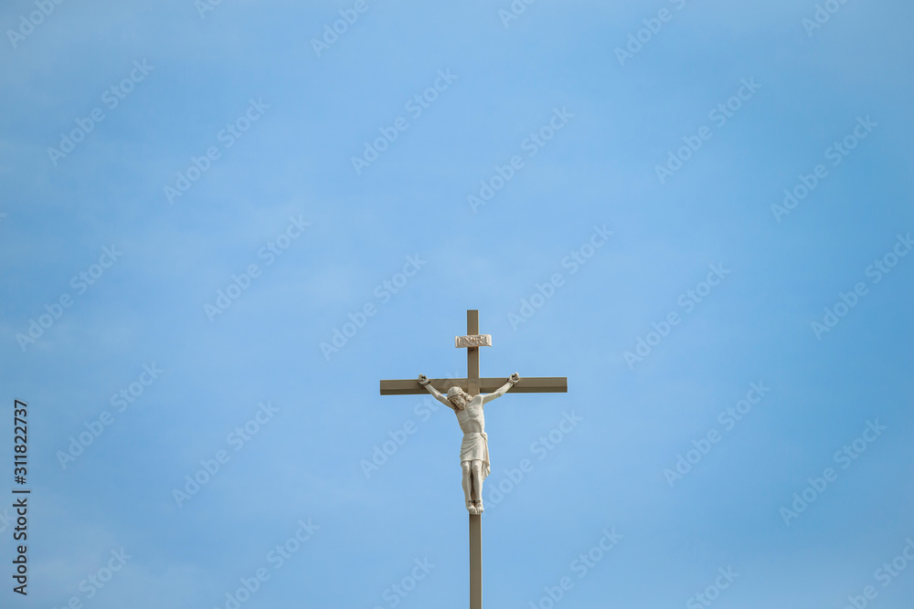Catholic Church's Statue of jesus on cross against blue sky, top of the world.