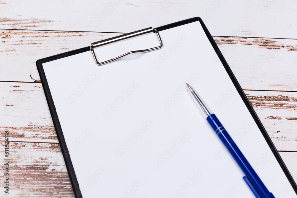 pen on blank white document sheet on wood clipboard on white wood table top view space pen on blank white document sheet on wood clipboard on white wood table top view space