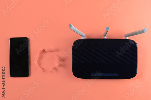 Wi-Fi router and smartphone on pink background with torn hole