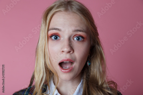 Confused surprised young blonde girl in plaid jacket opened her mouth in wonder what was going on