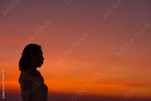 The black silhouette of a woman Background sky orange light of sunset.