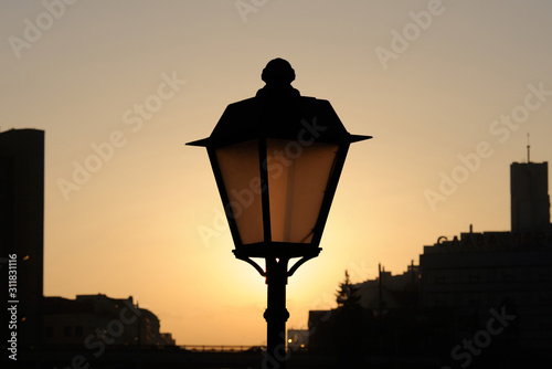 Electric lamps of city lighting on poles at the time of sunset