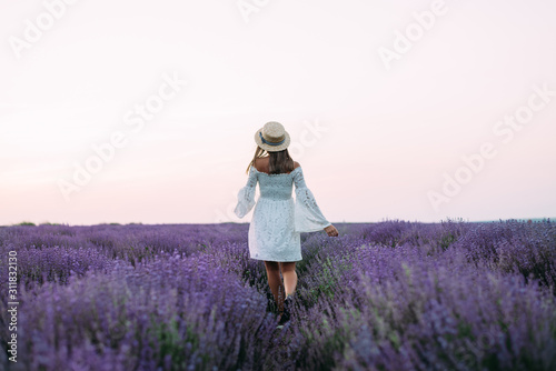 A young woman in a dress walks on a lavender field
