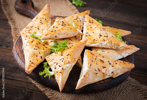 Asian food. Samsa (samosas) with chicken fillet and cheese on wooden background.