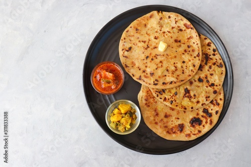 Indian Food - Aloo Paratha or Indian Potato stuffed Flatbread. Served with butter for breakfast, pickle and masala potatoes among with Indian Tea or masala chai.  with copy space. photo