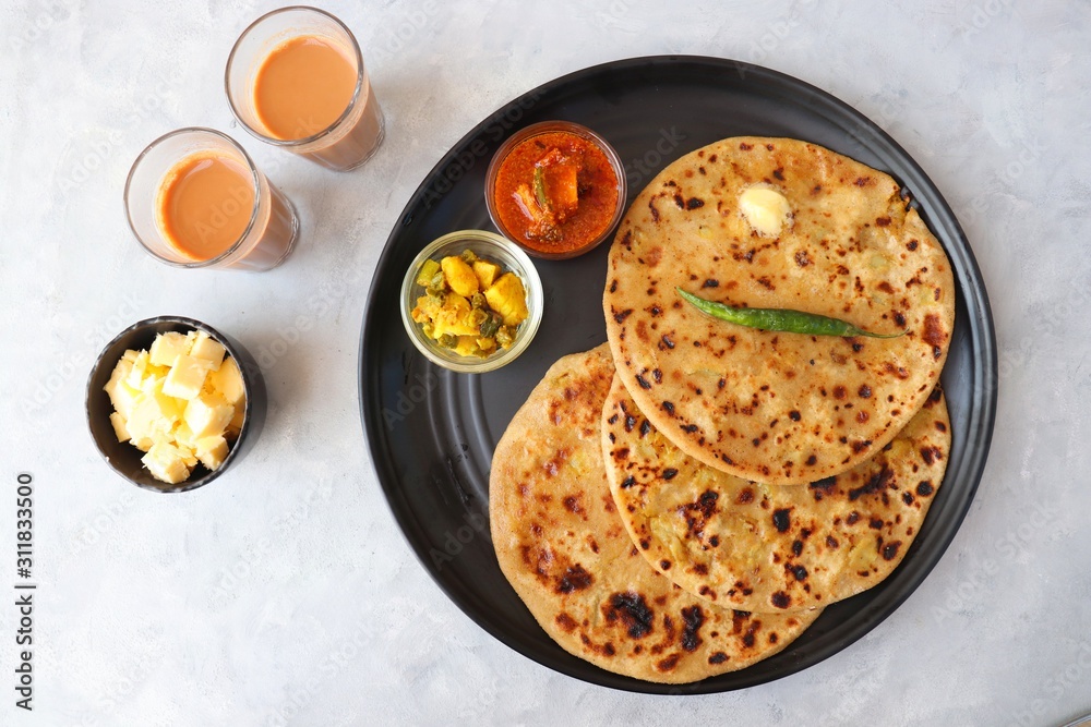 Indian Food - Aloo Paratha or Indian Potato stuffed Flatbread. Served with butter for breakfast, pickle and masala potatoes among with Indian Tea or masala chai. with copy space. Indian Food - Aloo Paratha or Indian Potato stuffed Flatbread. Served with butter for breakfast, pickle and masala potatoes among with Indian Tea or masala chai. with copy space.