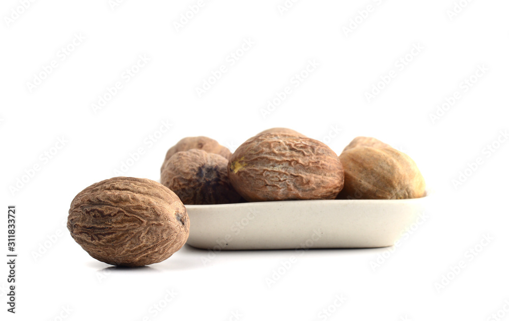 Nutmeg in white plate isolated on white background Nutmeg in white plate isolated on white background