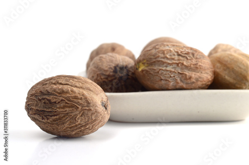 Nutmeg in white plate isolated on white background photo