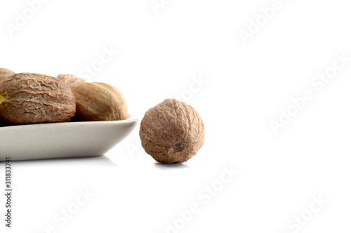 Nutmeg in white plate isolated on white background photo