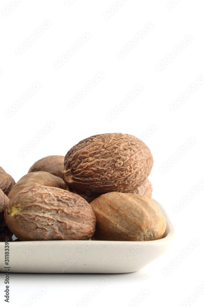 Nutmeg in white plate isolated on white background Nutmeg in white plate isolated on white background