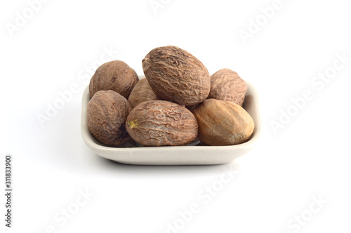 Nutmeg in white plate isolated on white background photo