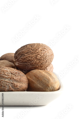 Nutmeg in white plate isolated on white background photo