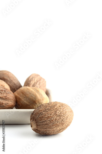 Nutmeg in white plate isolated on white background photo