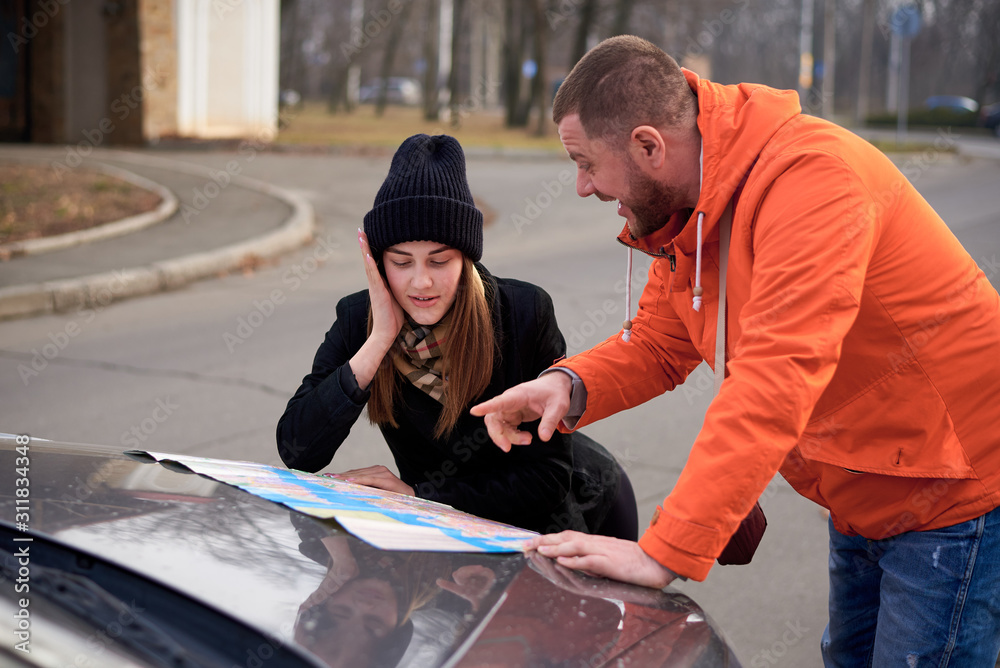 Young people argue near a car with a map on the road. Young people argue near a car with a map on the road.