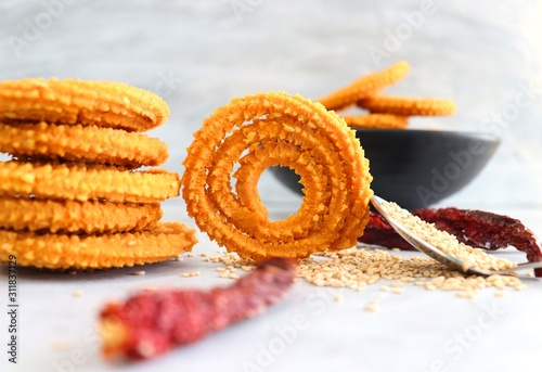 Crunchy fried homemade Chakli in a bowl with sesame seeds. Chakli is a savory snack from India made out of rice, mixed yellow and green lentils along with spices. Mostly eaten during Diwali festival