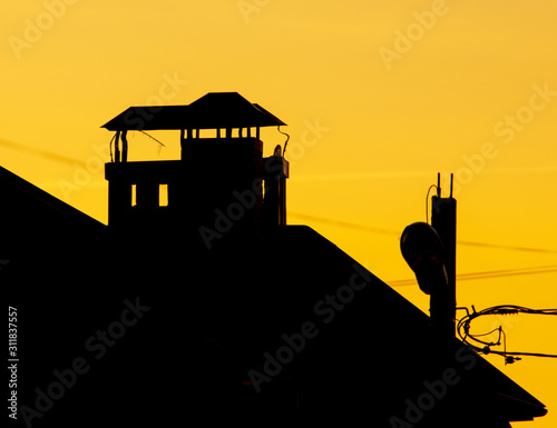 chimney on the roof of a house against the backdrop of a sunset © schankz