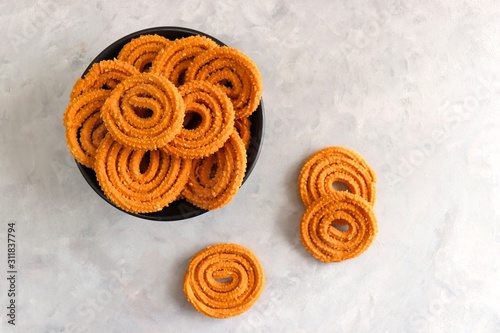 Crunchy fried homemade Chakli in a bowl with sesame seeds. Chakli is a savory snack from India made out of rice, mixed yellow and green lentils along with spices. Mostly eaten during Diwali festival photo