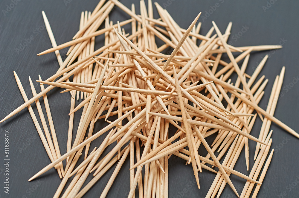 Heap of wooden toothpicks lies on black concrete desk on kitchen. Close-up Heap of wooden toothpicks lies on black concrete desk on kitchen. Close-up