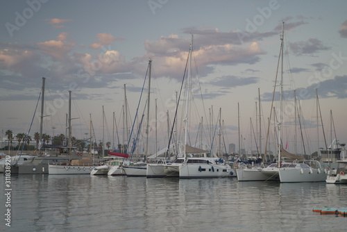 Luxury power boats in the Royal Marina in Valencia Spain, some moored,others sail on the sea. The city of Calpe in Spain, Valencia, Europe, in the cloudy evening 
