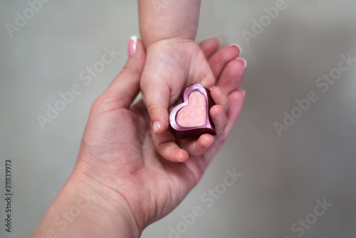Two girls holding a heart in its hands behind spring