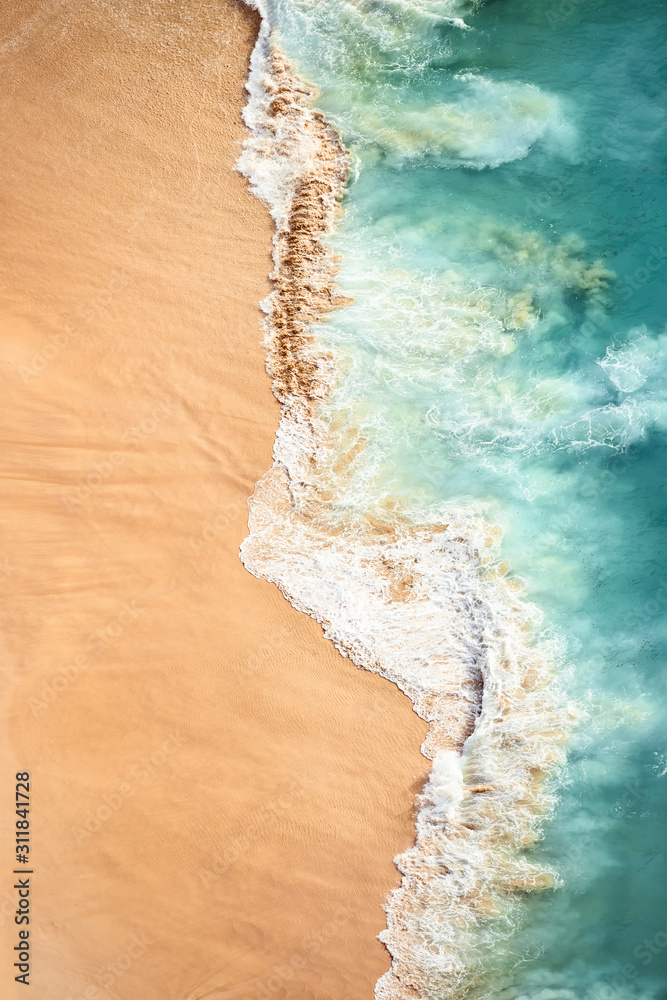 View from above, stunning aerial view of some waves crashing onto a beautiful beach during sunset. Kelingking beach, Nusa Penida, Indonesia.