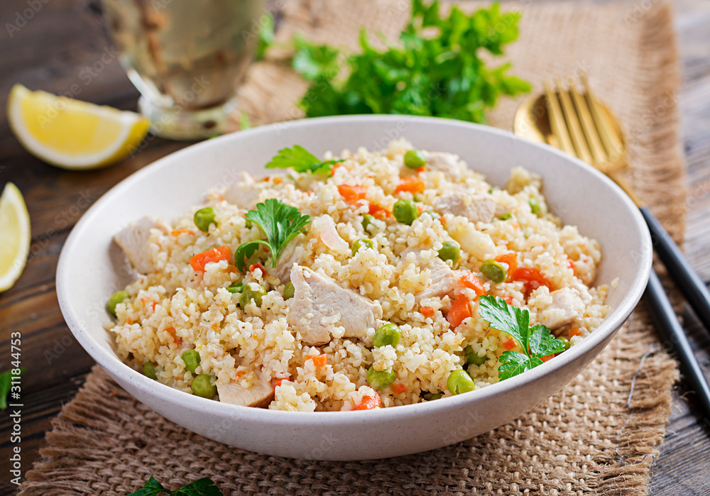 Bulgur with chicken, green peas and carrot on wooden background. Bulgur with chicken, green peas and carrot on wooden background.