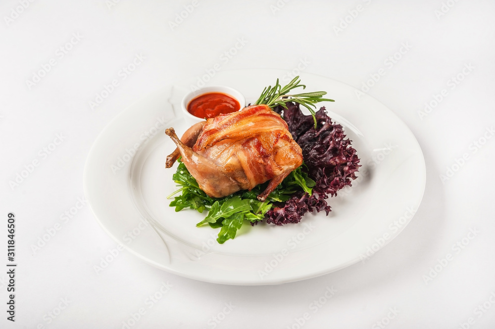 Quail stuffed in a restaurant close-up. Quail in bacon on a white plate and copy space. Quail stuffed in a restaurant close-up. Quail in bacon on a white plate and copy space.