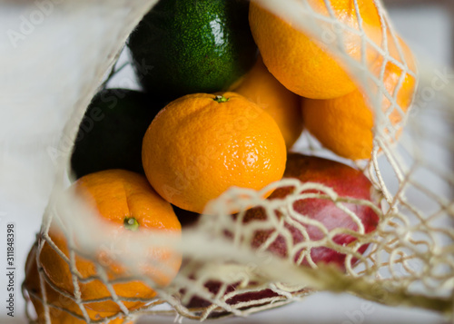 Fresh vegetables and fruits in the eco koton bag and net bag. Mesh bag with mango, avocado, apples, bell pepper and tangerines. Zero waste concept and plastic free. photo