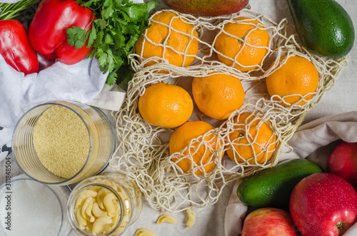 Fresh vegetables and fruits in the eco koton bag and net bag. Mesh bag with mango, avocado, apples, bell pepper and tangerines. Zero waste concept and plastic free. photo