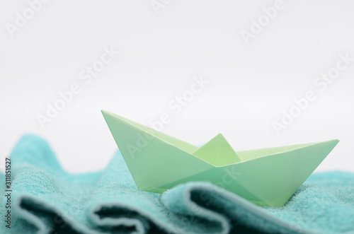 Paper ship sails on woolen fabric waves   hand crafted paper boat on fabric waves.