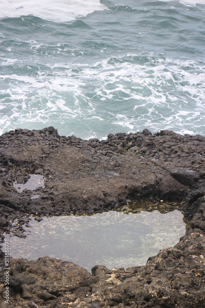 a puddle of water in the middle of a rock in the middle of the sea