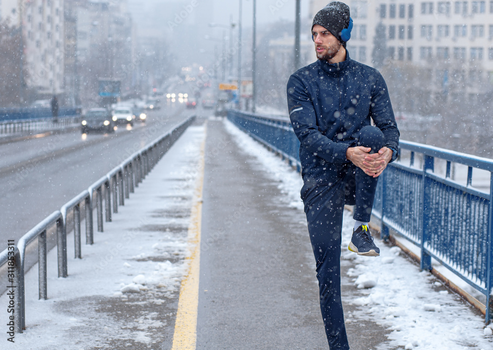 Young man stretching before running in city street at cold winter day. Young man stretching before running in city street at cold winter day.