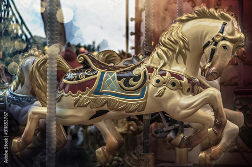 Horses on a children's carousel with bokeh in the square at the Christmas market.