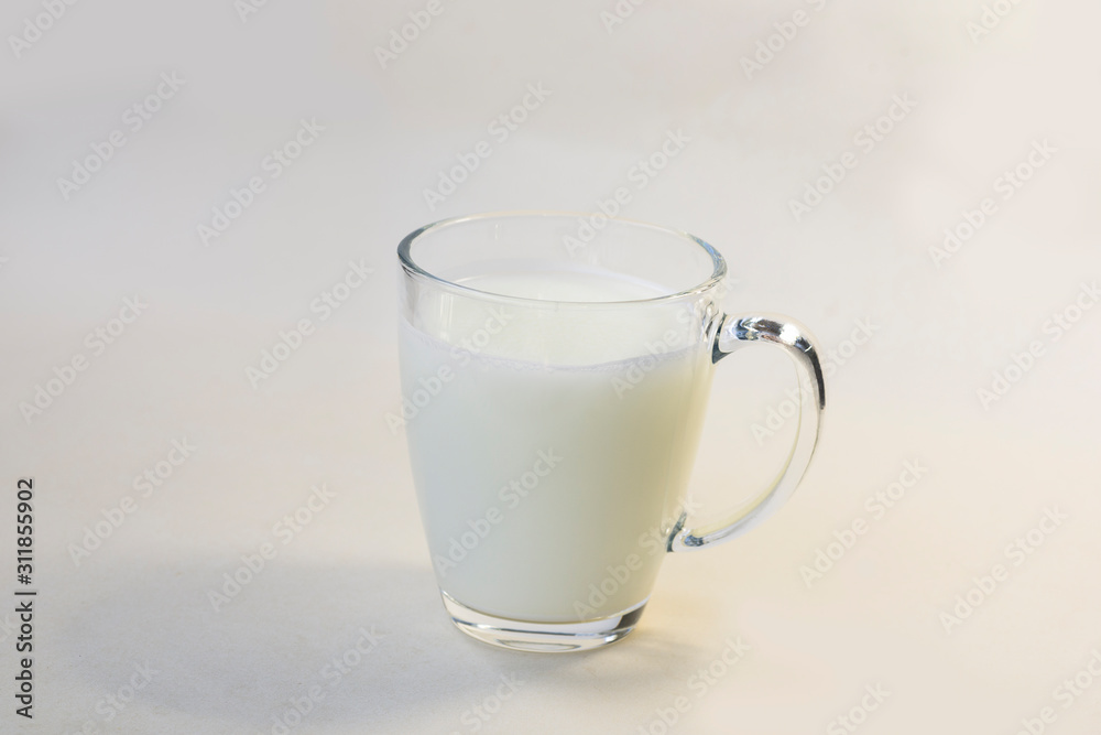 A cup of soy milk stands alone on a pale yellow background. A cup of soy milk stands alone on a pale yellow background.